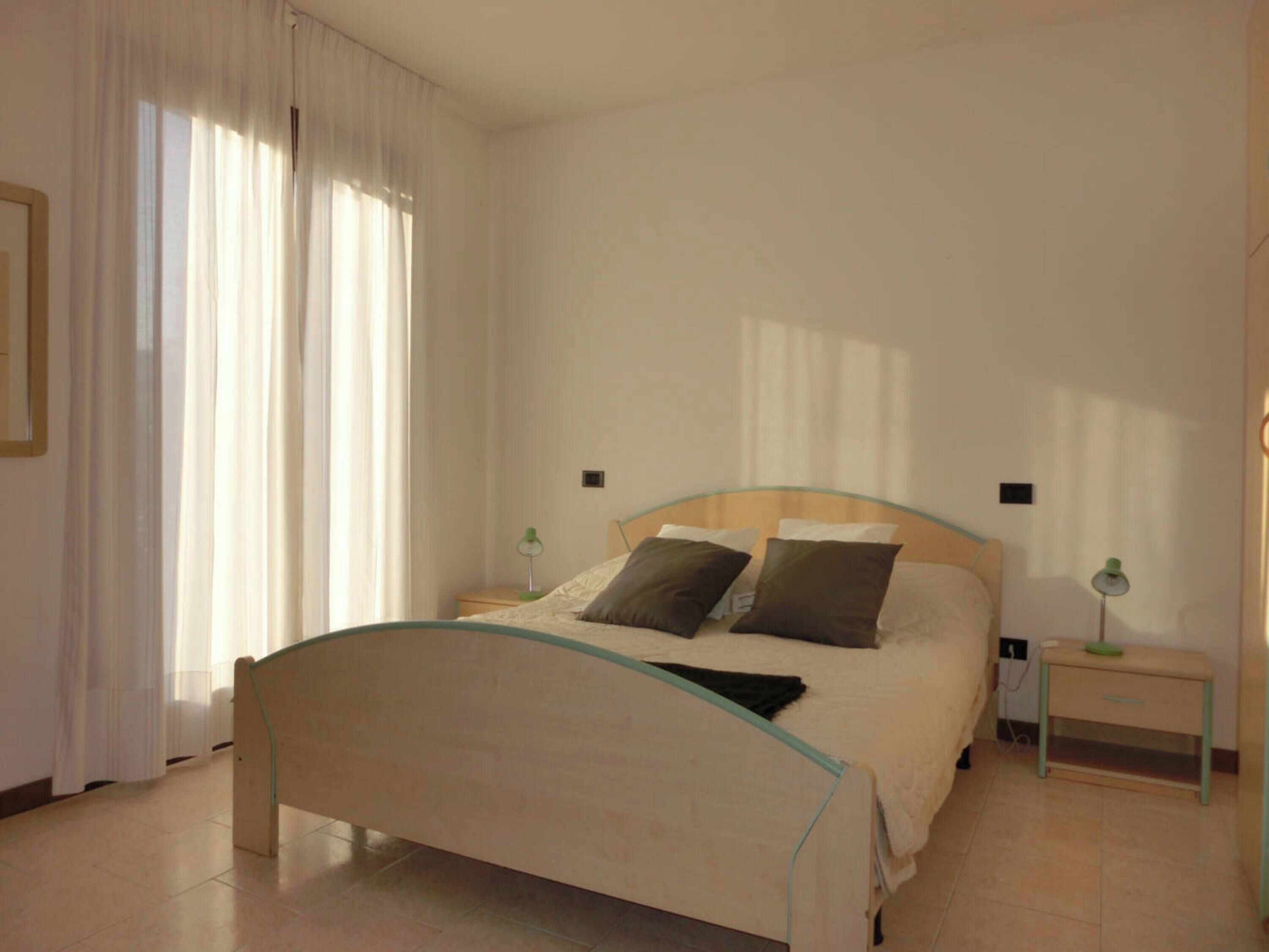Une chambre à coucher avec un lit, deux tables de chevet et une fenêtre avec des rideaux.