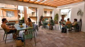 Un'area pranzo all'aperto coperta con diversi tavoli e sedie, circondata da edifici.