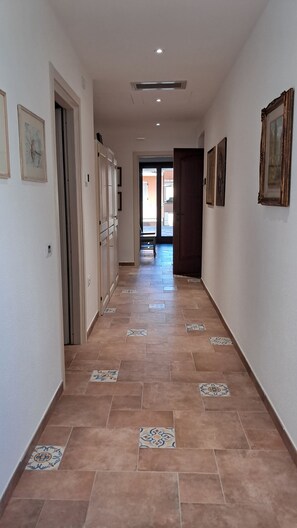 Un pasillo con baldosas estampadas, obras de arte enmarcadas en las paredes y una puerta que da a otra habitación.