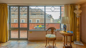A room with a large window, a chair, a table with a lamp, and a bust sculpture. - Charme and View in the Heart of Rome (Rome)