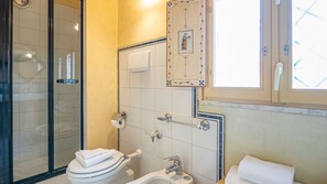Un baño con cabina de ducha de vidrio, inodoro, lavabo y toallero.