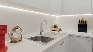 A modern kitchen with a stainless steel sink, white cabinets, and a red coffee machine. - Kolonaki Luxury Residence, Bill & John Apartments & Villas (Athens)