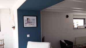 En moderne stue med en hvid lænestol, en blå væg og et indrammet billede.