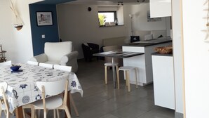 Et moderne køkken med hvide skabe og et spiseområde med et bord dækket til fire personer.