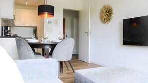 A modern kitchen with a dining area, a flat-screen TV, and a decorative wall piece. - Cozy Paradise Apartment – Relaxation with Pool & Sauna (Schluchsee)