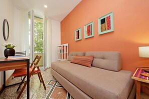 A cozy living area with a sofa, a dining table, and chairs. There are framed artworks on the wall and a window providing natural light. - Riboty House al Vaticano (Roma)