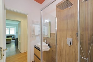 A modern bathroom with a glass shower enclosure, a wooden vanity, and a mirror. - Riboty House al Vaticano (Roma)