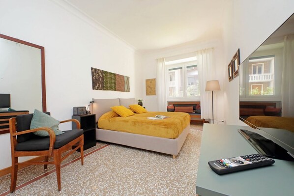 A hotel room with a bed, a desk, a chair, a TV, and a window with curtains. - Riboty House al Vaticano (Roma)