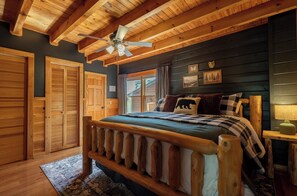 A wooden bedroom with a bed, ceiling fan, and wooden walls. - Best View In The Smokies! Hot Tub, Firepit, Games! (Pigeon Forge)