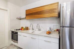 Eine moderne Küche mit weißen Schränken, einem Edelstahl-Kühlschrank, einer Holzablage und einem Spülbecken mit Armatur.