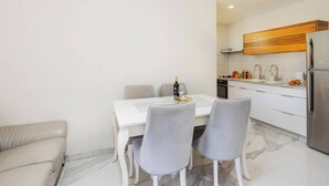 A modern kitchen with white cabinets, a wooden accent wall, and a stainless steel refrigerator. - 1 BR Apartment in Schneller Jerusalem Israel (Jerusalem)