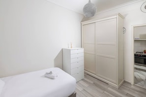 Ein Schlafzimmer mit Bett, Kommode, Kleiderschrank und einer Küchenzeile.