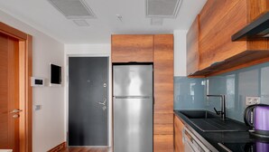 Une cuisine moderne avec un réfrigérateur en acier inoxydable, des armoires en bois, un plan de travail noir et un appareil électroménager violet.