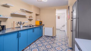 A kitchen with blue cabinets, a countertop with a coffee machine, a toaster, and shelves with glassware. - Comfortable Home Steps from the Kadıköy Waterfront (Istanbul)