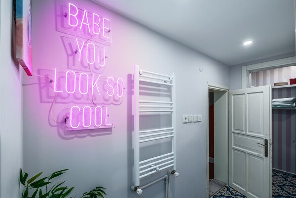 Un couloir avec un panneau néon sur lequel on peut lire : « Tu es vraiment géniale » et un radiateur blanc.
