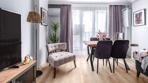 A modern living room with a TV, seating, a dining area, and a large window with curtains. - Stylish New Apartment with Fast WiFi (Istanbul)
