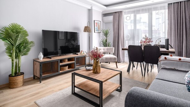 A modern living room with a flat-screen TV, a coffee table, a sofa, and a dining area with chairs. - Stylish New Apartment with Fast WiFi (Istanbul)