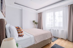 Ein ordentlich eingerichtetes Schlafzimmer mit Bett, Kissen, einer Lampe und einem Fenster mit Vorhängen.