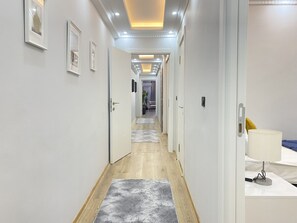 Ein moderner Hotelgang mit Holzboden, weißen Wänden und gerahmten Kunstwerken.