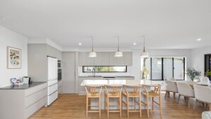 Une cuisine moderne avec des meubles blancs, un îlot central et des luminaires suspendus.