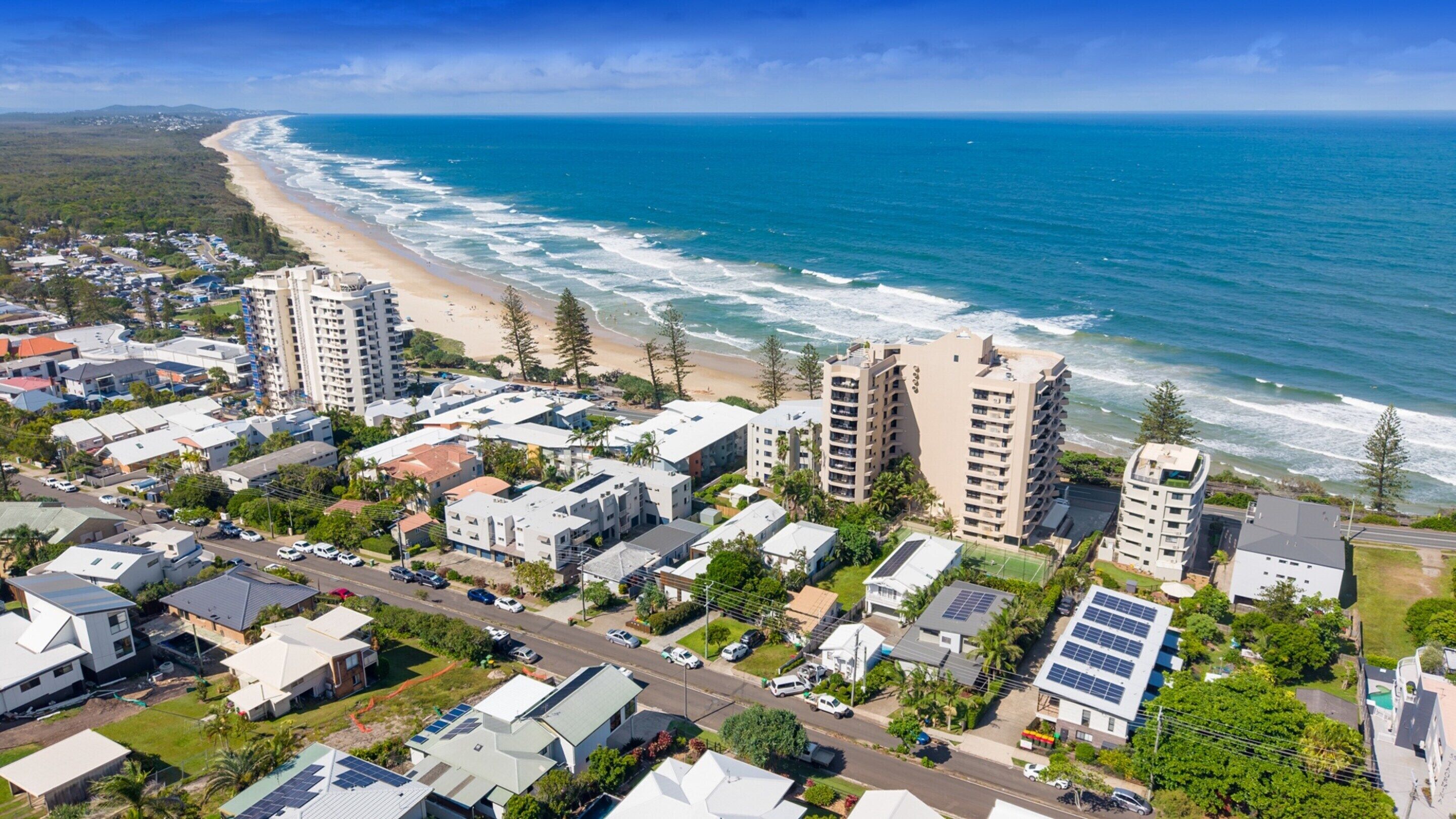 Una zona residencial costera con propiedades frente al mar, incluyendo edificios de varios pisos y casas unifamiliares.