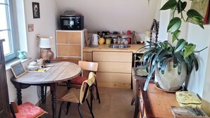 Cocina compacta con microondas, lavamanos y comedor con mesa y sillas.