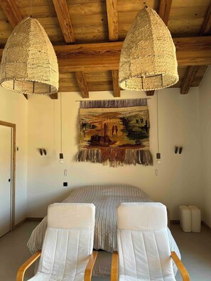 A bedroom with a bed, two chairs, a tapestry, and wooden ceiling beams. - Family chalet in the Alps with a great view and 3 separate living areas. (Notre-Dame-de-Bellecombe)