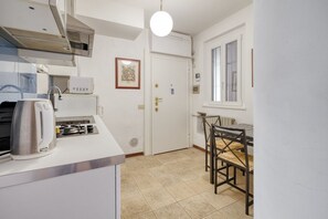 A compact kitchen with a toaster, microwave, and a single chair. - Hostmate - Milano - Savona - Solari (Milano)