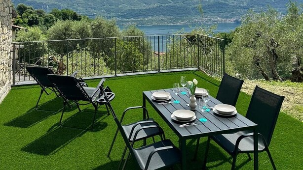 A terrace with a table set for dining, overlooking a mountainous landscape and a body of water. - Casa L'Olivér Apartment Casaliva with Private Terrace and Lake View (Limone sul Garda)