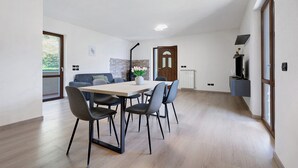 A modern dining area with a table and chairs, a sofa, and a fireplace. - Casa L'Olivér Apartment Casaliva with Private Terrace and Lake View (Limone sul Garda)