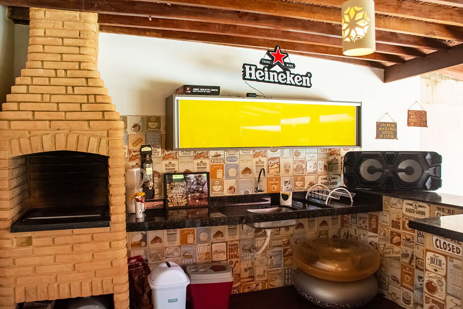 Een keuken met een bakoven, een Heineken bord, een groot geel scherm en wandtegels in vintage stijl.