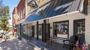 A storefront with a metal awning, a sign for 'KORWOOD DESIGN CO.', and a window displaying 'CUSTOM CABINETS, FURNITURE & MORE'. - Fully Updated 2 Bedroom Apartment in Downtown - Just Steps Away from Green Lake (Green Lake)