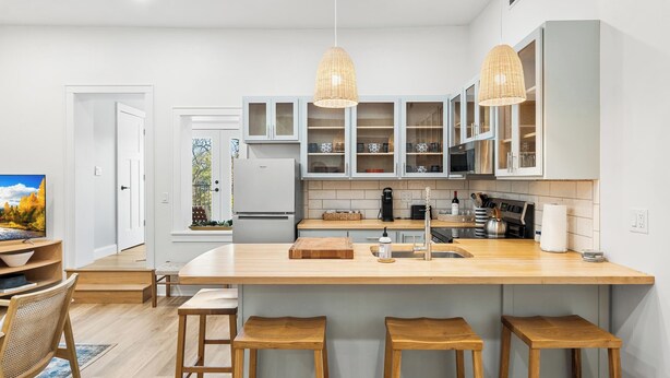 A modern kitchen with a central island, wooden stools, and pendant lighting. - Fully Updated 2 Bedroom Apartment in Downtown - Just Steps Away from Green Lake (Green Lake)