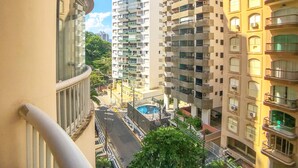 Um edif ício residencial alto com várias varandas, área de piscina e vista para o bairro ao redor.