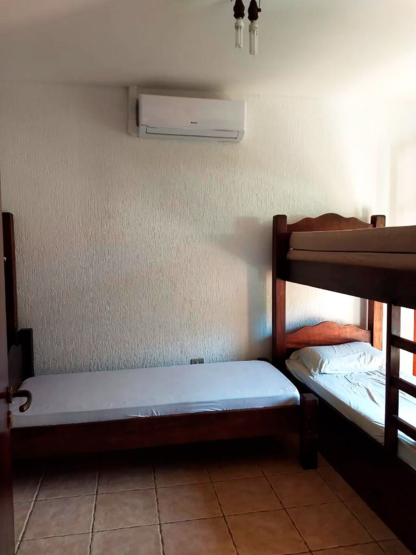 Il s’agit d’un petit logement composé d’une seule pièce, comprenant un lit superposé et un lit simple. Il y a également un ventilateur de plafond et un appareil de climatisation.