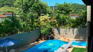 A backyard with a swimming pool, lounge chairs, and a patio table. - Incrível casa a 13 min a pé da Praia de Juquehy/SP (São Sebastião)