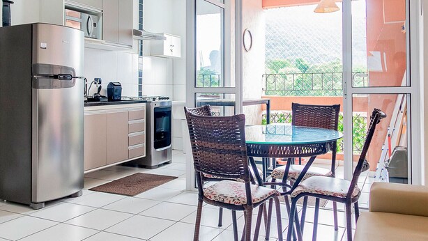 Una cucina moderna con forno integrato e zona pranzo con sedie in vimini e tavolo in vetro.