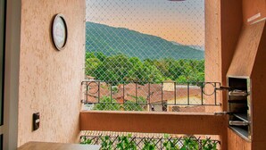 Un balcone con vista su un paesaggio montuoso, una lampada a sospensione e un cancello in metallo.