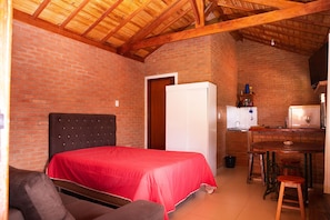 A small, cozy room with a bed, a desk, and a kitchenette.