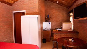 Uma cozinha compacta com pia, uma geladeira pequena e uma mesa de madeira com dois banquinhos.