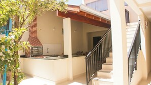 A modern kitchen with a brick oven, a staircase, and a view of the backyard. - Apto c Churrasqueira próx do Centro- Campo Grande (Campo Grande)