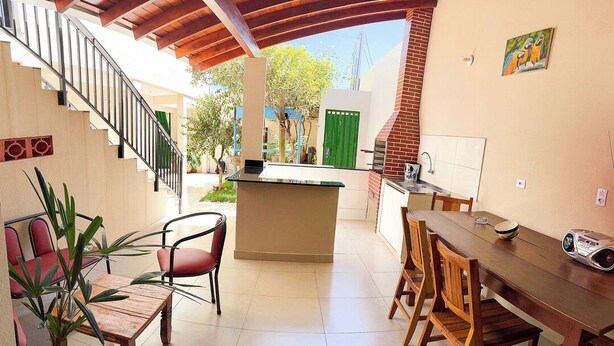 A spacious patio with a wooden table and chairs, a small bar area, and a staircase leading to an upper level. - Apto c Churrasqueira próx do Centro- Campo Grande (Campo Grande)