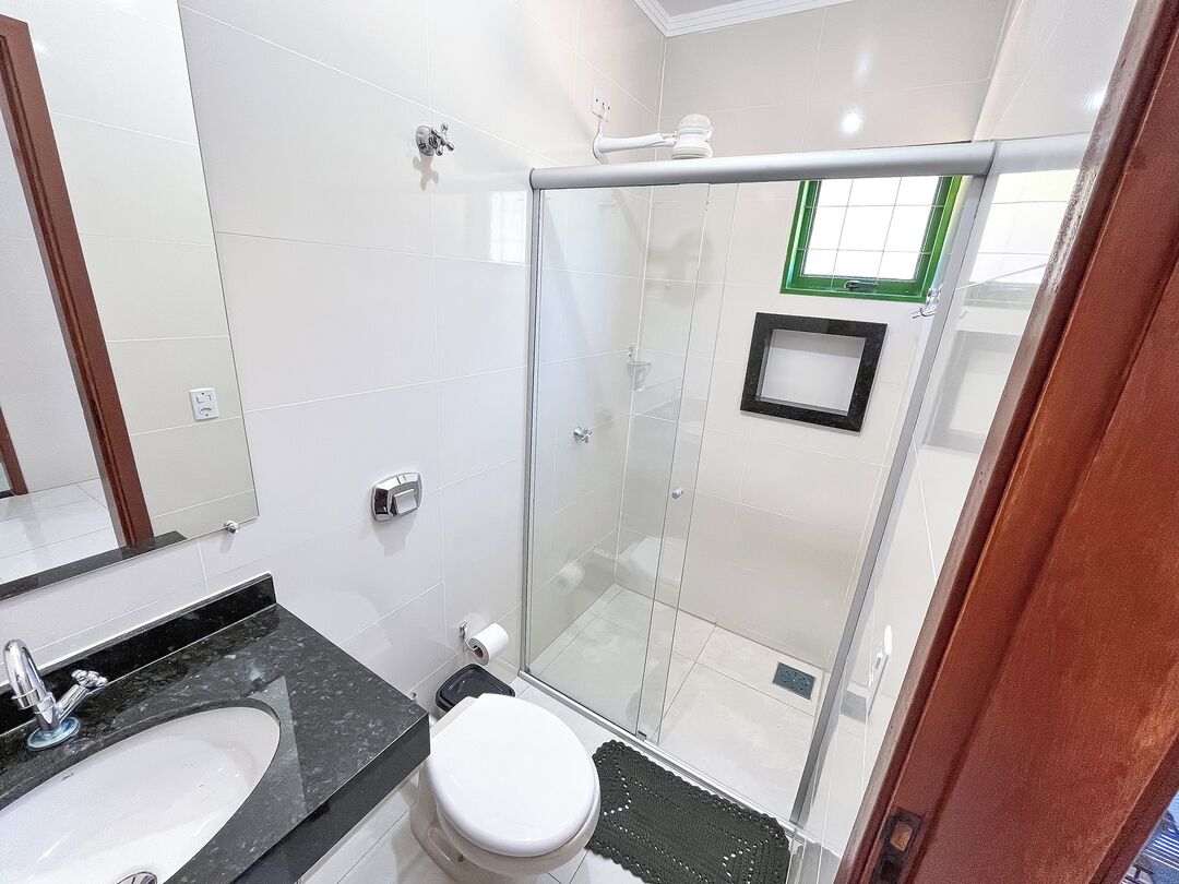 Une salle de bain avec une douche à parois de verre, un lavabo doté d’un plan de toilette noir et des toilettes.