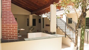 A spacious kitchen with a brick wall, a wooden ceiling, and a staircase leading to an upper level. - Apto c Churrasqueira próx do Centro- Campo Grande (Campo Grande)