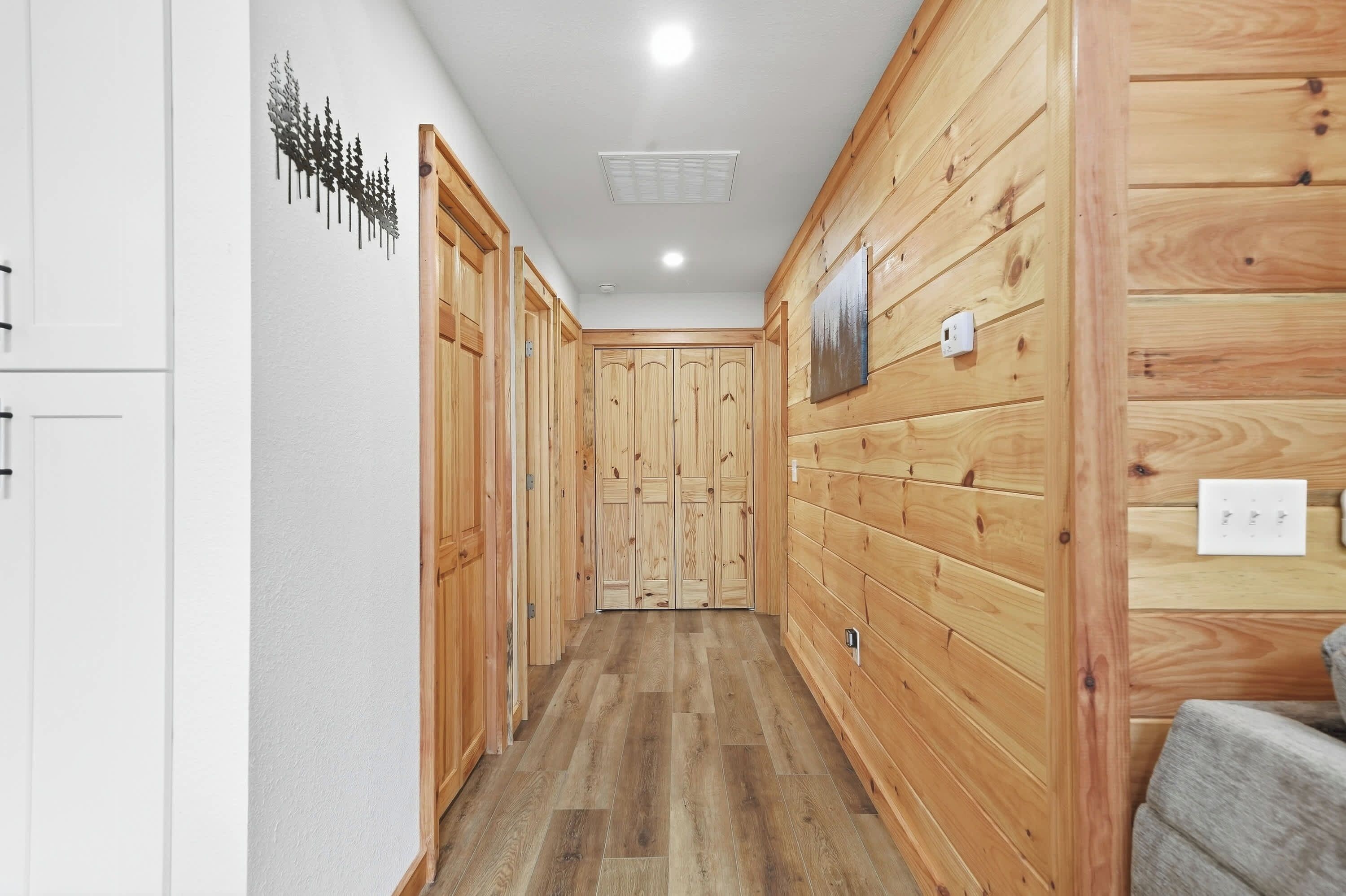 A hallway with wooden paneling, a white ceiling, and a wooden floor.