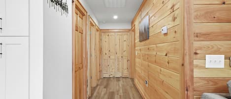 A hallway with wooden paneling, a white ceiling, and a wooden floor.