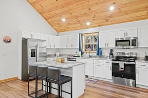 A modern kitchen with white cabinetry, stainless steel appliances, and a wooden ceiling. - Embers Place - Murphy (Murphy)
