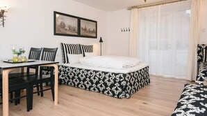 A bedroom with a bed, a desk with chairs, a dining table, and a window with curtains. - 4 Star Holiday Home in Skanderborg (Skanderborg)