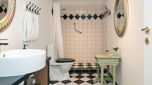 A bathroom with a white sink, black and white checkered floor, a green vanity, a toilet, and a shower with a white curtain. - 4 Star Holiday Home in Skanderborg (Skanderborg)