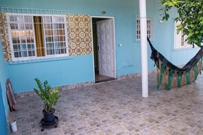 A building with a tiled floor, a hammock, and a potted plant. - Casa Pet Friendly a 950m da Praia Vista Linda (Bertioga)